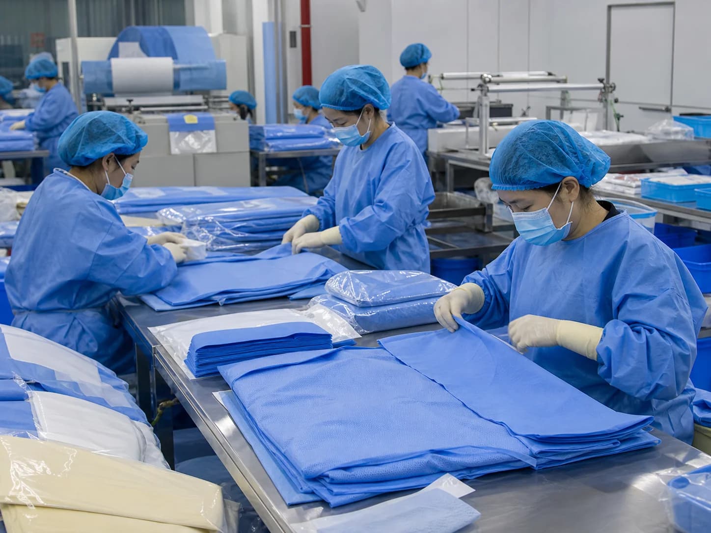 Chinese medical disposable factory workers inspecting and preparing blue surgical non-woven products