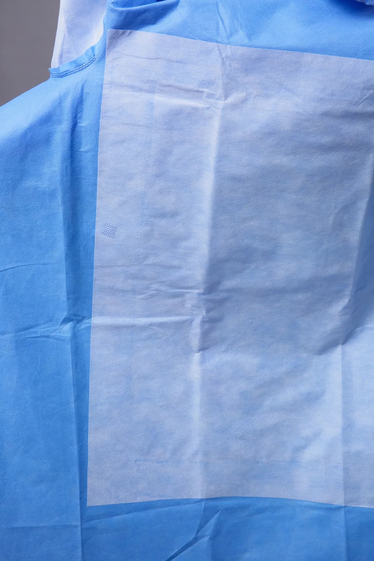 Detalle real del panel reforzado y material no tejido de una bata quirúrgica